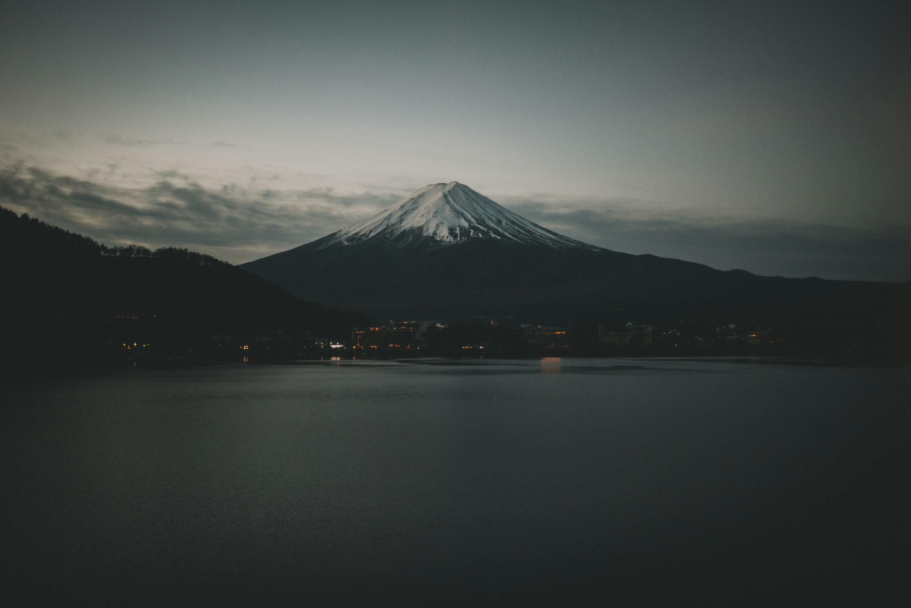 Mount Fuji above a dark lake at dusk